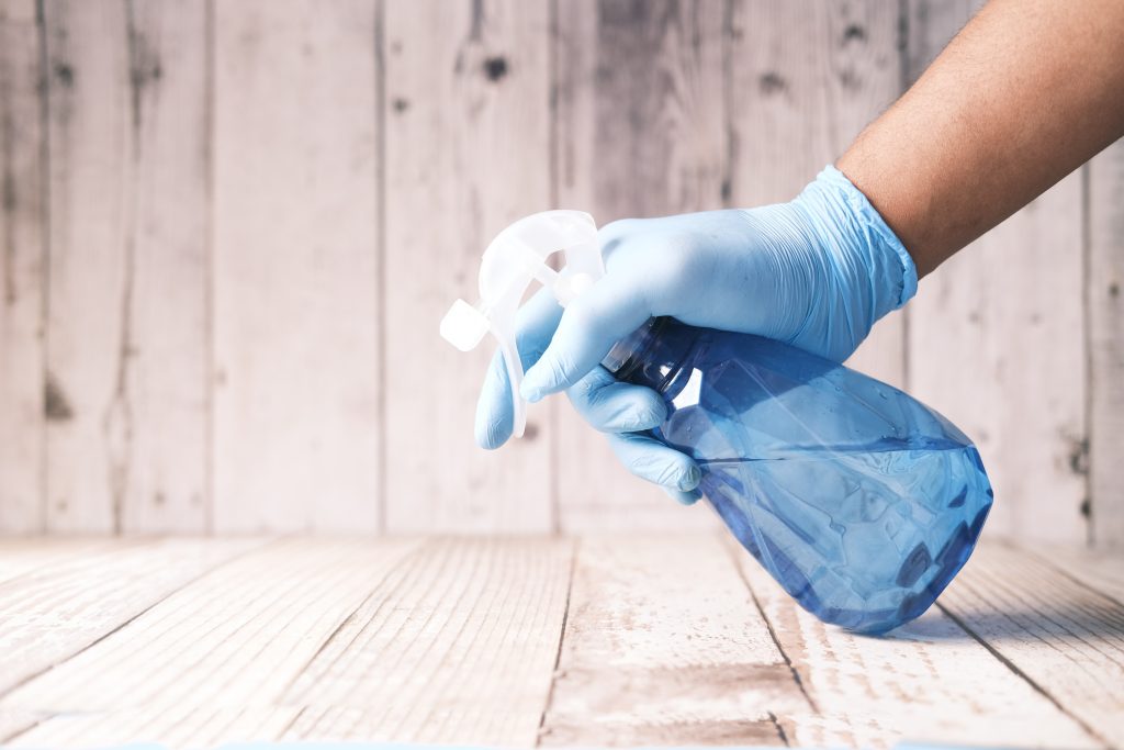 someone holdign a cleaning spray bottle with a blue latex glove on