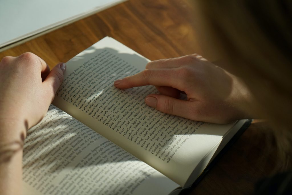 someone reading a book, following the words with their finger